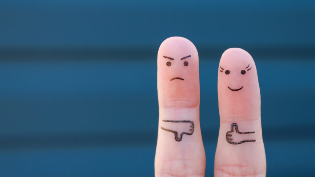 zwei Finger, angemalt wie Personen. Eine lächelt und zeigt den Daumen hoch. Die andere schaut grimmig und zeigt den Daumen nach unten